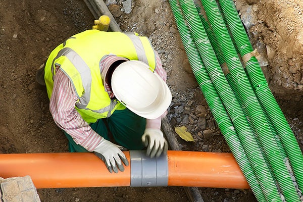 worker installing hdpe corrugated pipe with double wall strength at the construction site on street city